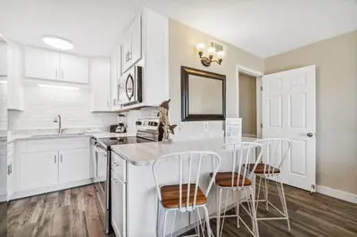 a kitchen with white cabinets and a counter with stools at The Summit 108 in Panama City Beach