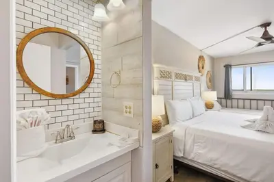 a white bedroom with a large bed and a mirror at The Summit 1322 in Panama City Beach