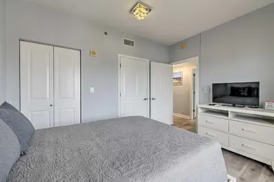 a white bedroom with a bed and a tv at Oceanfront PCB Resort Condo with Balcony and Views! in Panama City Beach