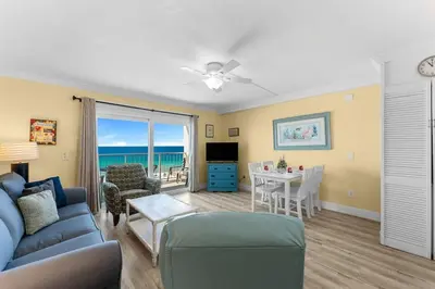 a living room with a blue couch and a dining room with the ocean at The Summit 726 in Panama City Beach