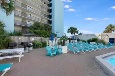 a patio with blue chairs and a swimming pool at Top Of The Gulf 111 in Panama City Beach