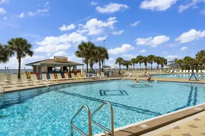 a large swimming pool with palm trees and a beach at The Summit 306 in Panama City Beach