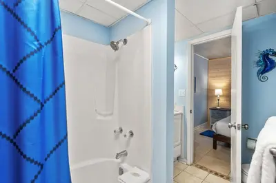 a bathroom with a blue shower curtain and a sink at Sunbird 811E in Panama City Beach