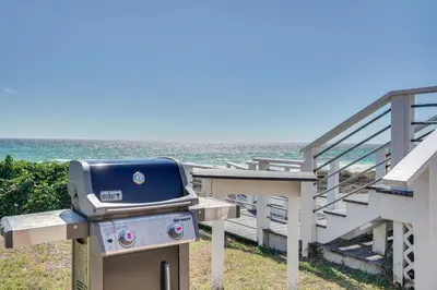 a grill sitting next to a staircase next to the ocean at Breezy PCB Retreat with Direct Beach Access! in Panama City Beach