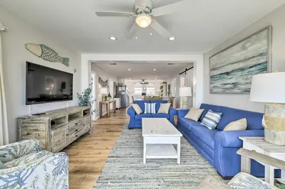 a living room with a blue couch and a tv at Breezy PCB Retreat with Direct Beach Access! in Panama City Beach