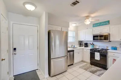 a kitchen with white cabinets and a stainless steel refrigerator at Sun-Dappled PCB Retreat with Multiple Pools! in Panama City Beach