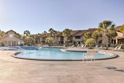 a large swimming pool with chairs and palm trees at Sun-Dappled PCB Retreat with Multiple Pools! in Panama City Beach