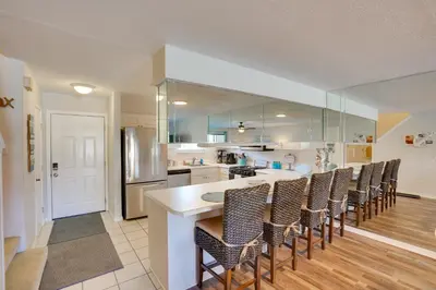a kitchen with a bar with chairs and a counter at Sun-Dappled PCB Retreat with Multiple Pools! in Panama City Beach