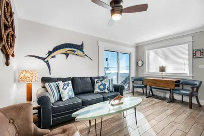a living room with a couch and a dolphin on the wall at Sand Castles West II G4- FinView in Panama City Beach