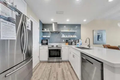 a kitchen with white cabinets and a stainless steel refrigerator at Sterling Breeze 904 in Panama City Beach