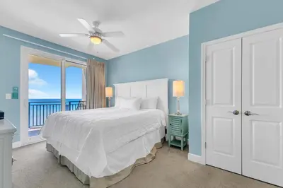 a blue bedroom with a bed and a window at Sterling Breeze 904 in Panama City Beach