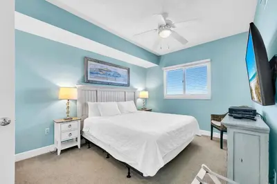 a bedroom with a white bed and a blue wall at Sterling Breeze 904 in Panama City Beach