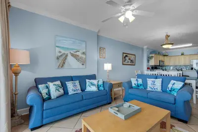 a living room with two blue couches and a table at Ocean Villa 1101 in Panama City Beach