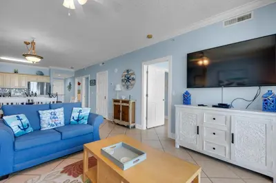 a living room with a blue couch and a tv at Ocean Villa 1101 in Panama City Beach