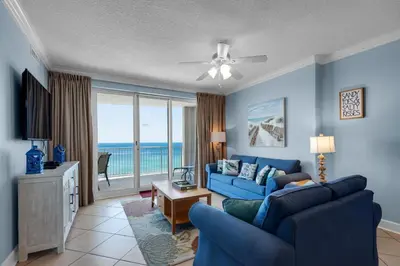 a living room with a blue couch and a tv at Ocean Villa 1101 in Panama City Beach