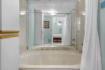 a bathroom with a tub with a large mirror at Edgewater Tower 2-307 in Panama City Beach