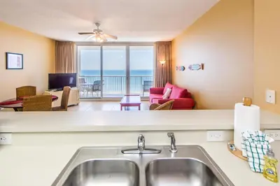 a kitchen with a sink and a living room at Majestic Beach Towers 1-1706 in Panama City Beach