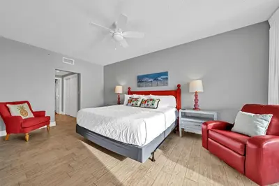 a bedroom with a bed and a red chair at Majestic Beach Towers 2-1701 in Panama City Beach