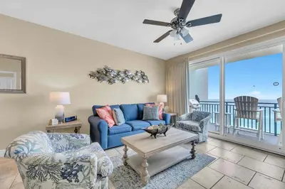 a living room with a blue couch and chairs and a balcony at Sterling Breeze 802 in Panama City Beach