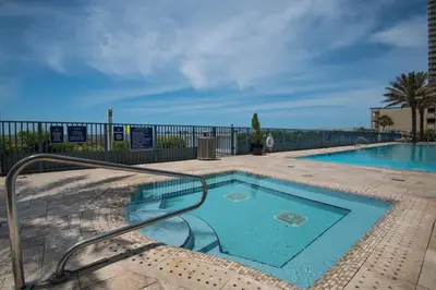 a swimming pool with a metal railing next to a fence at Sterling Breeze 802 in Panama City Beach
