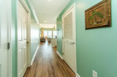 a hallway with green walls and wooden floors and a painting on the wall at Sterling Beach #602 in Panama City Beach