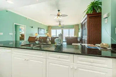 a kitchen with a sink and a living room at Sterling Beach #602 in Panama City Beach