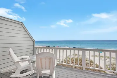 a deck with two chairs and a table on the beach at SeaRenity at Inlet 2 in Panama City Beach