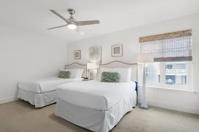 two beds in a white room with a ceiling fan at SeaRenity at Inlet 2 in Panama City Beach