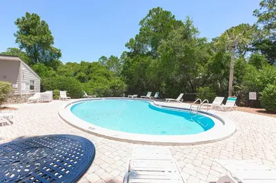 a large swimming pool with chairs and a table at Cassine Gardens 108- Sandy Daze in Santa Rosa Beach