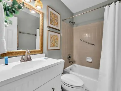 a bathroom with a sink and a toilet and a mirror at Cassine Gardens 108- Sandy Daze in Santa Rosa Beach