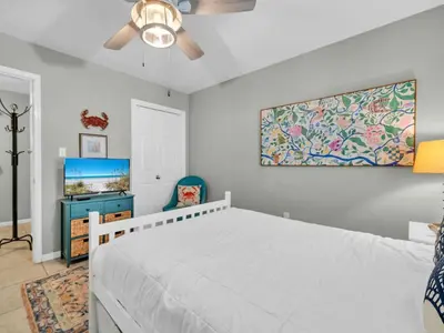 a bedroom with a white bed and a tv at Cassine Gardens 108- Sandy Daze in Santa Rosa Beach