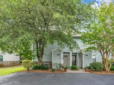 a white house with trees in front of it at Cassine Gardens 108- Sandy Daze in Santa Rosa Beach