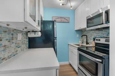 a kitchen with white cabinets and a black refrigerator at Top of the Gulf 713 in Panama City Beach