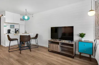 a living room with a television and a table and chairs at Top of the Gulf 713 in Panama City Beach