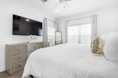 a white bedroom with a large bed and a tv at Legacy 505- Pearl by the Sea in Santa Rosa Beach