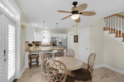 a kitchen with a table and chairs and a ceiling fan at Sunset Serenade in Rosemary Beach