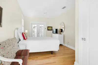 a white bedroom with a white bed and a chair at Sunset Serenade in Rosemary Beach