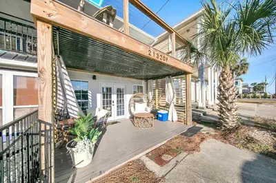 a house with a deck with a chair and palm trees at Modern Beach Bungalow in Panama City Beach