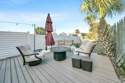 a patio with two chairs and an umbrella and a table at Modern Beach Bungalow in Panama City Beach