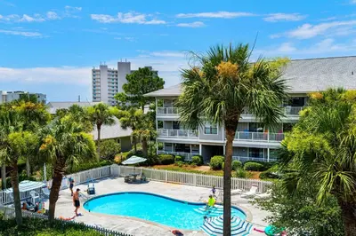 a swimming pool with palm trees in front of a building at Beachwood Villas 12C in Santa Rosa Beach