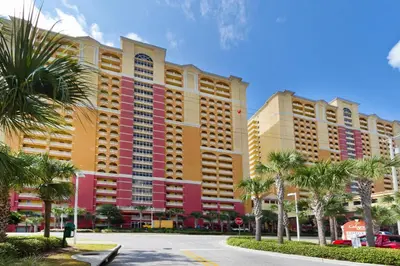 a large building with palm trees in front of a street at Calypso 1-2109 East in Panama City Beach
