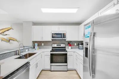 a kitchen with white cabinets and a stainless steel refrigerator at Calypso 3-807 in Panama City Beach