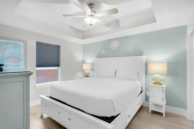 a white bedroom with a bed and a ceiling fan at Calypso 3-807 in Panama City Beach