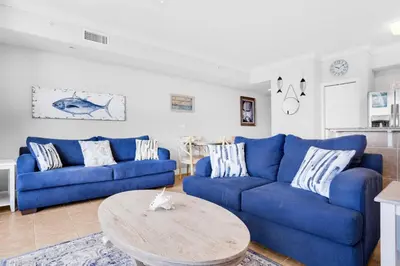 a living room with blue couches and a table at Tidewater 1810 in Panama City Beach