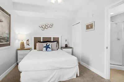 a white bedroom with a bed and two night stands at Tidewater 1810 in Panama City Beach