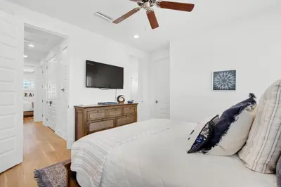 a white bedroom with a bed and a flat screen tv at Town of Prominence- Jetty's Hidden Jem in Inlet Beach