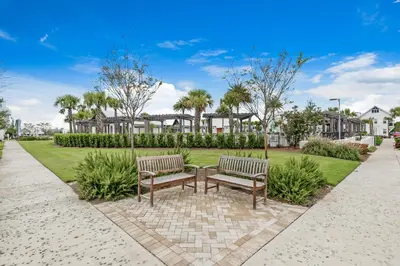 two benches in a park with palm trees and houses at Town of Prominence- Jetty's Hidden Jem in Inlet Beach