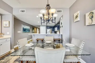 a dining room with a glass table and chairs at Majestic Beach Resort #204-2 by Book That Condo in Panama City Beach