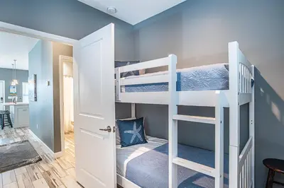 a room with two bunk beds and a kitchen at Beach Daze in Panama City Beach