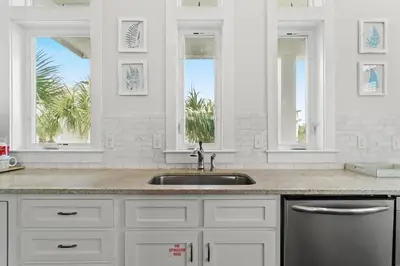 a white kitchen with a sink and two windows at FantaSea in Panama City Beach